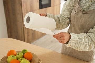 Housewife tearing off paper towel in kitchen, closeup