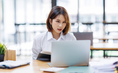 Portrait of happy asian female employee at computer
