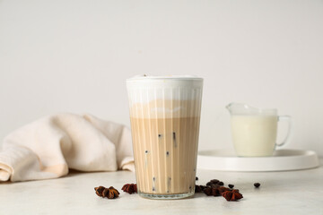Glass of iced latte and coffee beans on white background