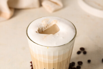 Glass of iced latte and coffee beans on white background