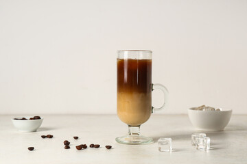 Glass cup of iced latte and coffee beans on white background