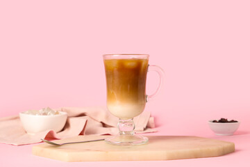 Glass cup of iced latte on pink background