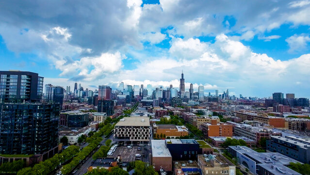 aerial drone footage of Chicago downtown area with lush green park with blue sky full of clouds The towering skyscrapers stand tall against a vast sky juxtaposition of urban development and nature