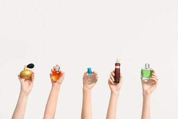 Female hands with different bottles of perfume on white background