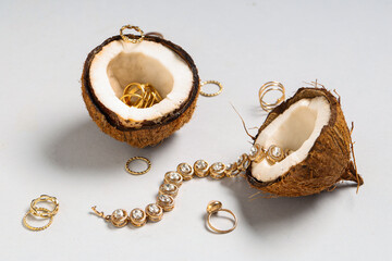 Fresh coconut with beautiful rings and necklace on grey background