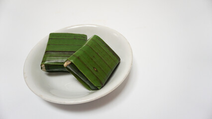 Lemper, a traditional snack from Indonesia, made from sticky rice, steamed with coconut milk, chicken floss inside, and wrapped with banana leaf. Served on white plate, isolated on white background