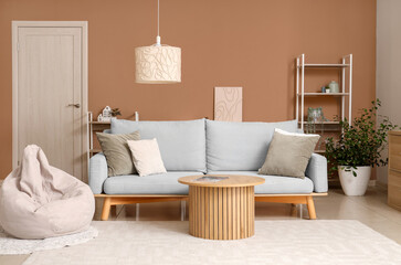 Interior of stylish living room with grey sofa, bean bag chair and wooden coffee table near beige wall