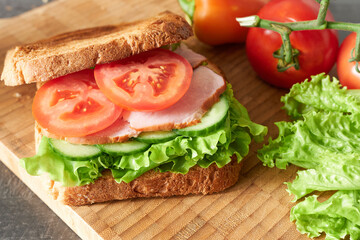 Making a breakfast sandwich. An appetizing sandwich on a wooden board.