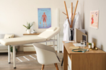 Blurred view of medical office with couch and doctor's workplace