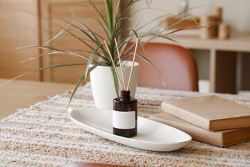 Reed diffuser, houseplant and books on table at home