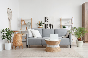 Interior of living room with sofa and laptop on rattan table