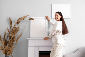 Young woman near fireplace with paintings at home