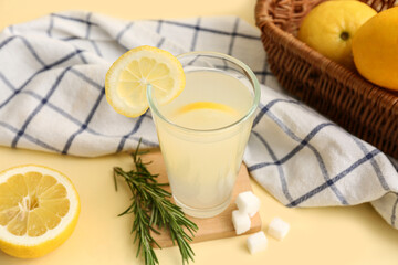 Glass of fresh lemonade with rosemary and sugar on yellow background