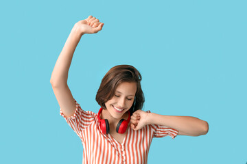 Happy young woman with modern headphones on blue background