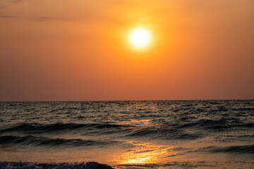 Fototapeta premium Big sun setting in Ocean painting orange the sky and the clouds