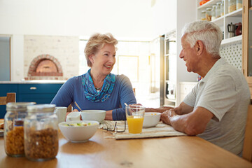 Elderly, couple and happy with eating at breakfast in dining room for nutrition, healthy meal and retirement. Senior, people and smile in home with conversation, relax or morning routine in apartment
