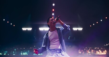 Stylish Asian RnB Pop Artist Delivering a Grand Performance in a Packed Concert Arena. Singer Standing on His Knees on Stage. Young Music Fans Enjoying Nightlife Entertainment