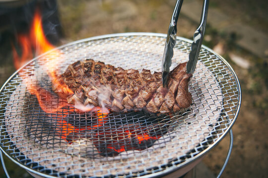 炭火で厚切りステーキを焼く