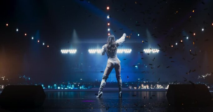 Music Contest: Back View of a Pop Music Artist Performing a Hit Song on Stage in Front of a Sold-Out Audience. Her Charismatic Stage Presence and Lyrics Electrify the Diverse Music Fans