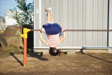 鉄棒で逆上がりをしている小学一年生の女の子