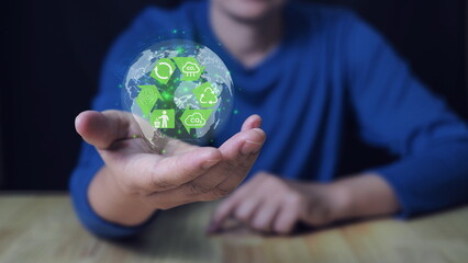 Green factory concept. Zero emission, Businessman holding globe with green factory icon on virtual screen for eco friendly industry production.