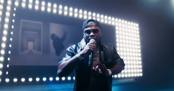 Rap Singer Performs Into a Camera on Stage Filled with Smoke and Colorful Spotlights. Hip Hop Artist Singing Songs to Thrilled Devoted Fans. Stunning Visuals Make for Creative Underground Atmosphere