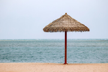 Straw umbrella on the beach in Doha on a cloudy day