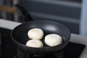 Hands of a female chef frying and baking homemade syrniki in a pan, sizzling in oil. Concept of home cooking, traditional recipes, and culinary preparation.