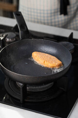 Fish cutlets sizzling in oil while frying in a pan on the stove. Concept of home cooking, traditional recipes, and culinary preparation.
