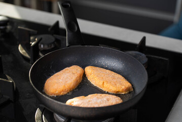 Fish cutlets sizzling in oil while frying in a pan on the stove. Concept of home cooking, traditional recipes, and culinary preparation.