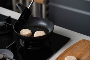 Meatballs or small meat patties cutlets sizzling in oil while frying in a pan on the stove. Concept of home cooking, traditional recipes, and culinary preparation