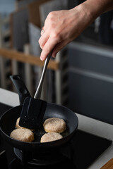 Meatballs or small meat patties cutlets sizzling in oil while frying in a pan on the stove. Concept of home cooking, traditional recipes, and culinary preparation