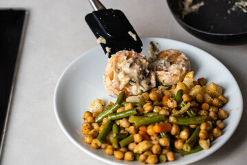 Meatballs or small meat patties cutlets sizzling in oil while frying in white sauce in a pan on the stove. Home cooking, traditional recipes, and culinary preparation