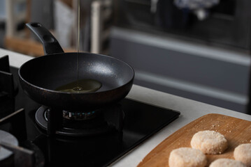 Meatballs or small meat patties cutlets sizzling in oil while frying in a pan on the stove. Concept of home cooking, traditional recipes, and culinary preparation