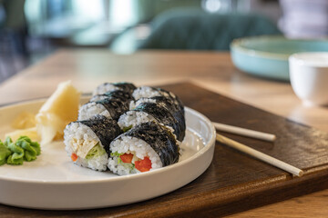 Vegetarian Sushi Rolls, Veggie sushi, wasabi, ginger on white plate  close up, Asian food in a modern café, restaurant, defocused cafe interior background.