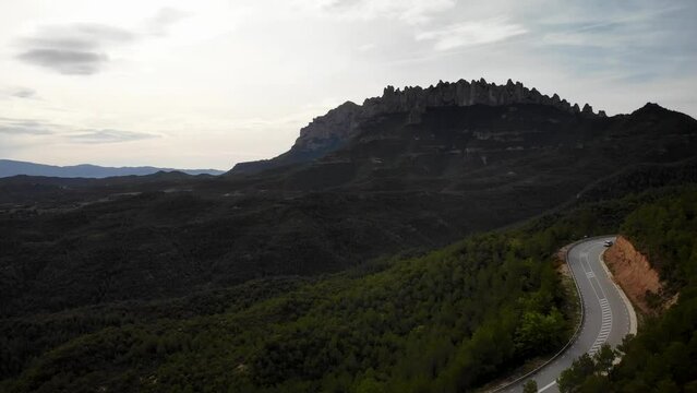 Mountain road with traffic pssing by at Montserrat mountain, Barcelona, Cataloia, Spain. High quality 4k drone view footage