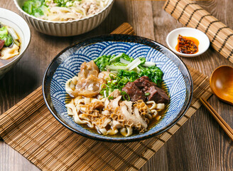 Sanbao Beef Noodles with chilli sauce, spring onion, wooden spoon, and chopsticks served in dish isolated on mat side view of taiwanese food
