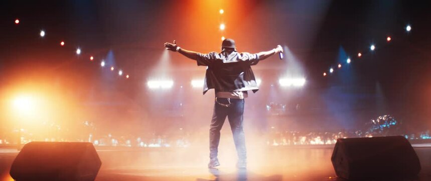 African Hip Hop Musician Delivers an Unforgettable Concert. Black Rapper Dancing on Stage, Charismatic Presence and Gangster Lyrics Captivate Music Goers. Footage From the Back. Anamorphic Shot