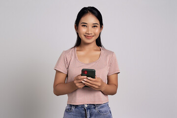 Smiling happy fun beautiful young Asian woman in a casual t-shirt checking new apps or social media, looking at camera isolated on white background