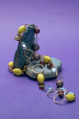 A necklace with yellow, black, and white stones draped over two rocks against a blue background.
