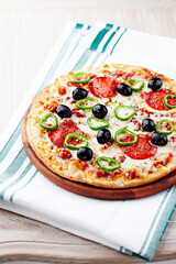 Pizza with salami, jalapeno pepper and black olives. Home made food. Concept for a tasty and hearty meal. Close up.