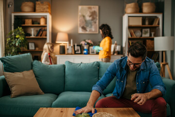 Obraz premium Man wiping and cleaning a table in the living room, his wife and daughter in the background