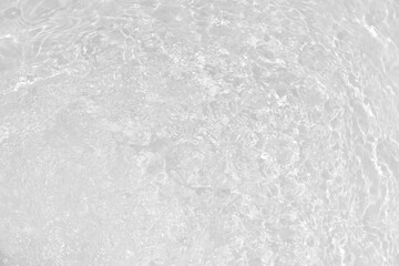 Obraz premium White water with ripples on the surface. Defocus blurred transparent white colored clear calm water surface texture with splashes and bubbles. Water waves with shining pattern texture background.