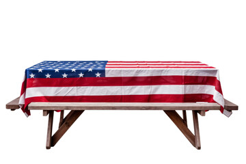 A wooden picnic table with a red, white, and blue American flag draped over it