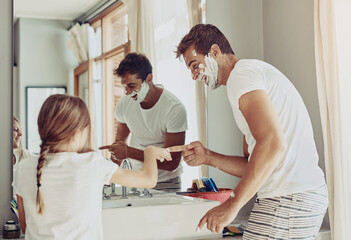 Father, family and child in bathroom playing with foam, cream and facial cleaning product at home. Excited dad, man or parent with kid for grooming beard, shaving and helping or learning in mirror