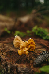 Handmade candles from natural beeswax in the shape of bear,  pine cones on an old stump in the forest. Hobby. Artistic photo of beekeeping products against the backdrop of nature