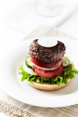Tasty hamburger with tomatoes and onion. Bright wooden background.