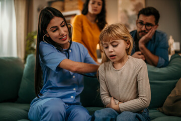 Doctor woman examining little girl with stethoscope in couch