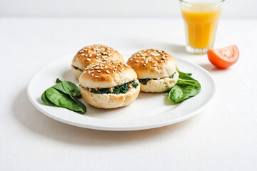 Freshly Made Spinach & Sesame Bagel Bites on a White Plate with a Glass of Orange Juice