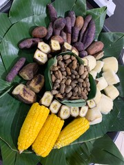 Delicious traditional Indonesian food such as bananas, cassava, sweet potatoes, peanuts, boiled corn is served with banana leaf pads on a tray made of woven bamboo